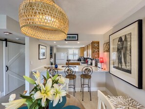 Modern kitchen with central island, sink, and appliances, complemented by a dining area with table for two.