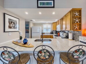 A modern kitchen with wooden cabinets, a white refrigerator, and a central island with bar stools. - Best Super Comfy Stay
ON NSB-Immaculate & 5 Stars
⭐️⭐️⭐️⭐️⭐️! (New Smyrna Beach)