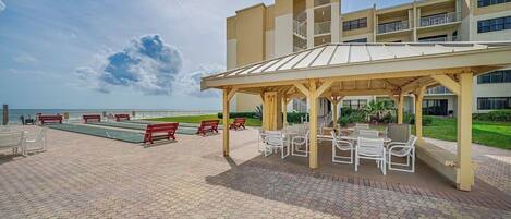 A covered outdoor area with seating and a pool view.