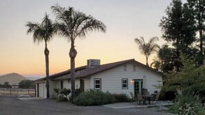 A single-story house with a garage, surrounded by a gravel driveway and palm trees. - Country Home at the Crossroads (Springville)
