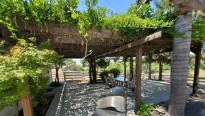 A covered outdoor seating area with tables and chairs, surrounded by greenery and trees. - Country Home at the Crossroads (Springville)