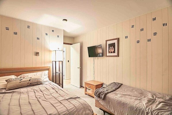 A bedroom with two beds, a TV, and a wardrobe. - Relaxation + Recreation @ Poconos.House (Lake Harmony)