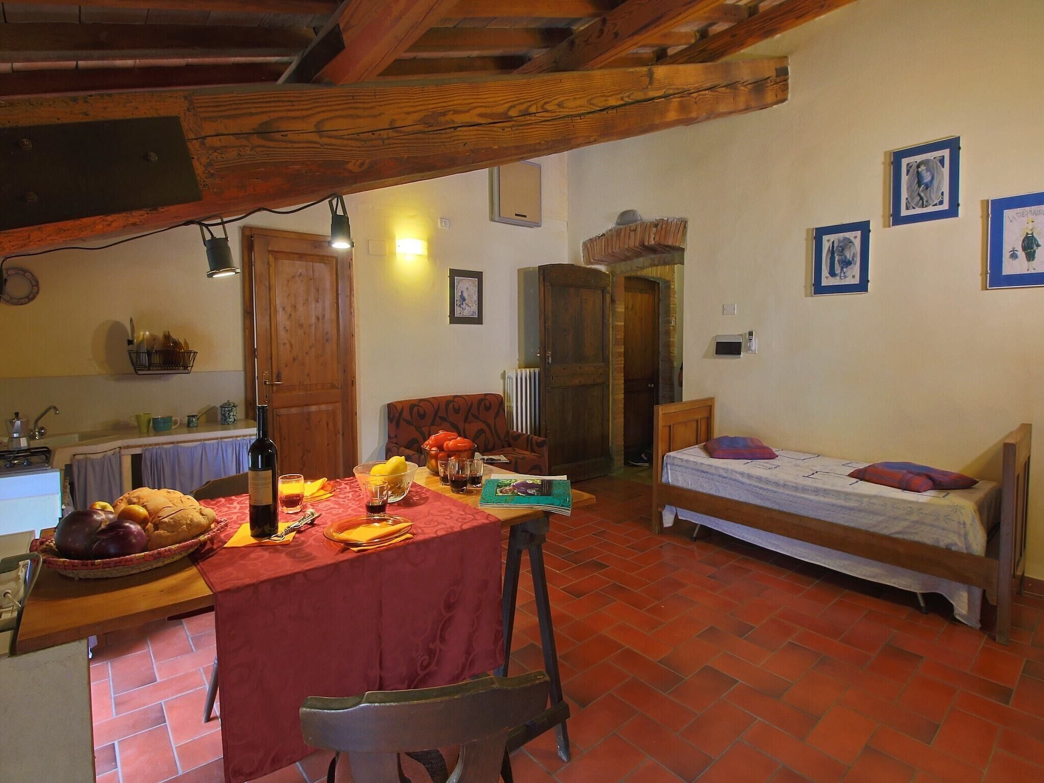 A cozy room with a dining table set for a meal, a bed, and a kitchen area.