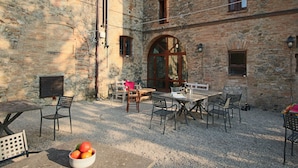 An outdoor patio with stone walls, a wooden table, and chairs. - Farmhouse in Umbertide with Pool (Umbertide)