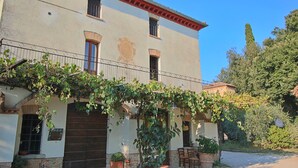 A two-story building with a balcony, potted plants, and a rustic facade. - Farmhouse in Umbertide with Pool (Umbertide)
