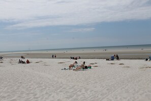 Ein Strand mit Menschen, die am Sand entspannen und im Wasser liegen.