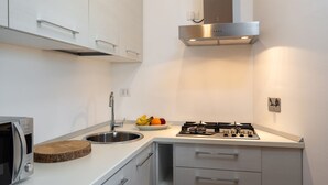 A compact kitchen with a built-in microwave, stainless steel sink, and gas stove.