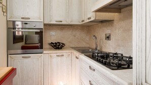 Una cocina con armarios de madera, horno empotrado, microondas, fregadero y estufa a gas.