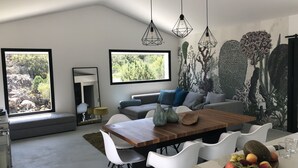 A modern kitchen with a dining area, large windows, and a mural of trees.