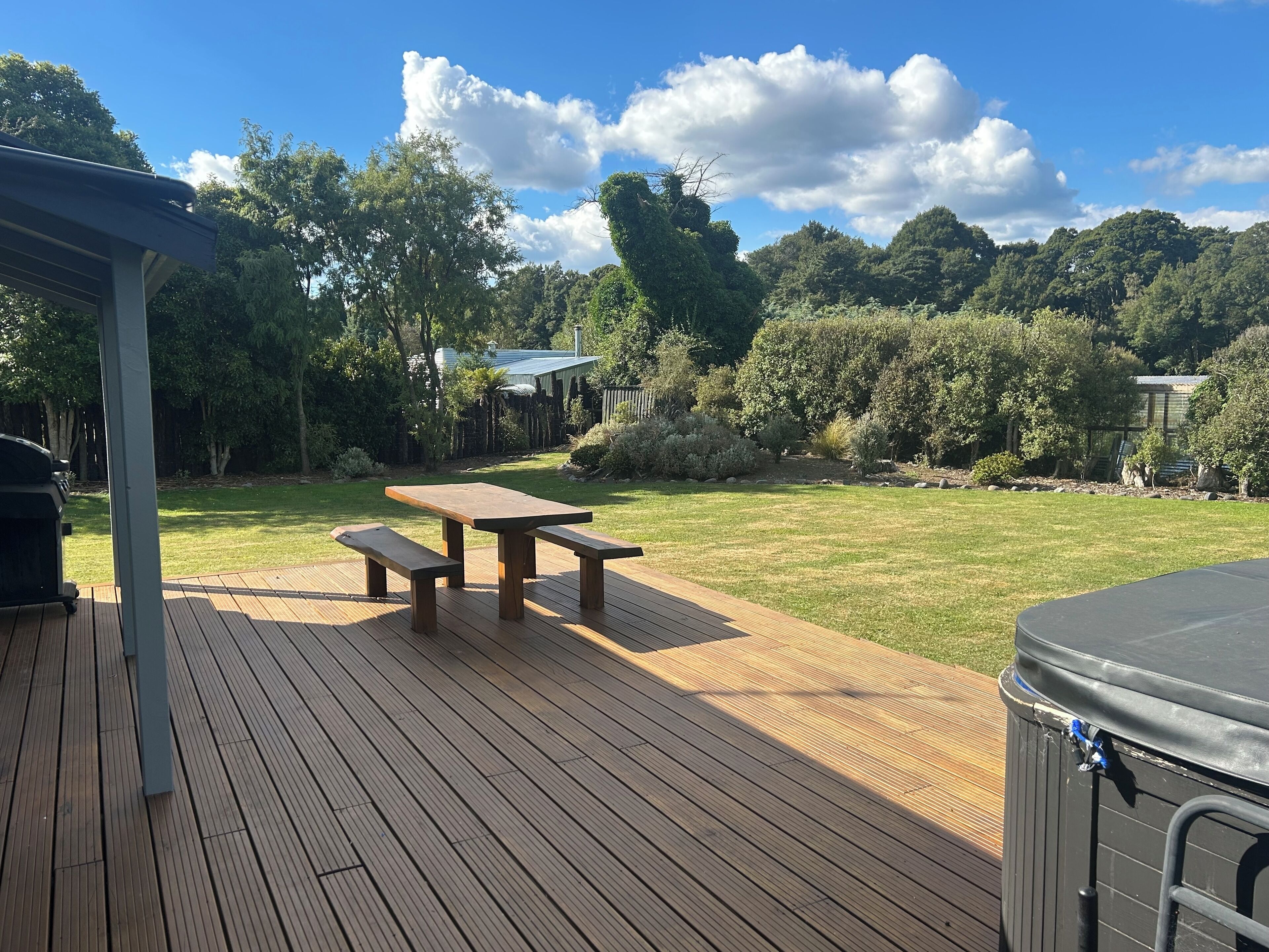 A wooden deck with picnic tables and a hot tub.