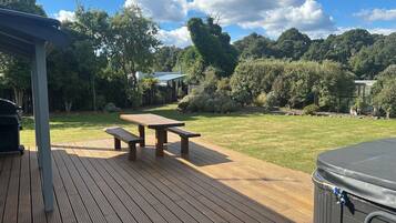 A wooden deck with picnic tables and a hot tub.