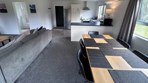 A modern apartment with a living area, kitchen, and dining space. - Alpine Bach with spa and separate games room. (Ohakune)