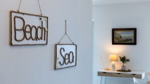 Two rustic wall decorations spelling "Beach" and "Sea" in a room with a white desk, a lamp, and a framed picture on the wall. - Two bedroom apartment with wonderful sea view (Mimice)