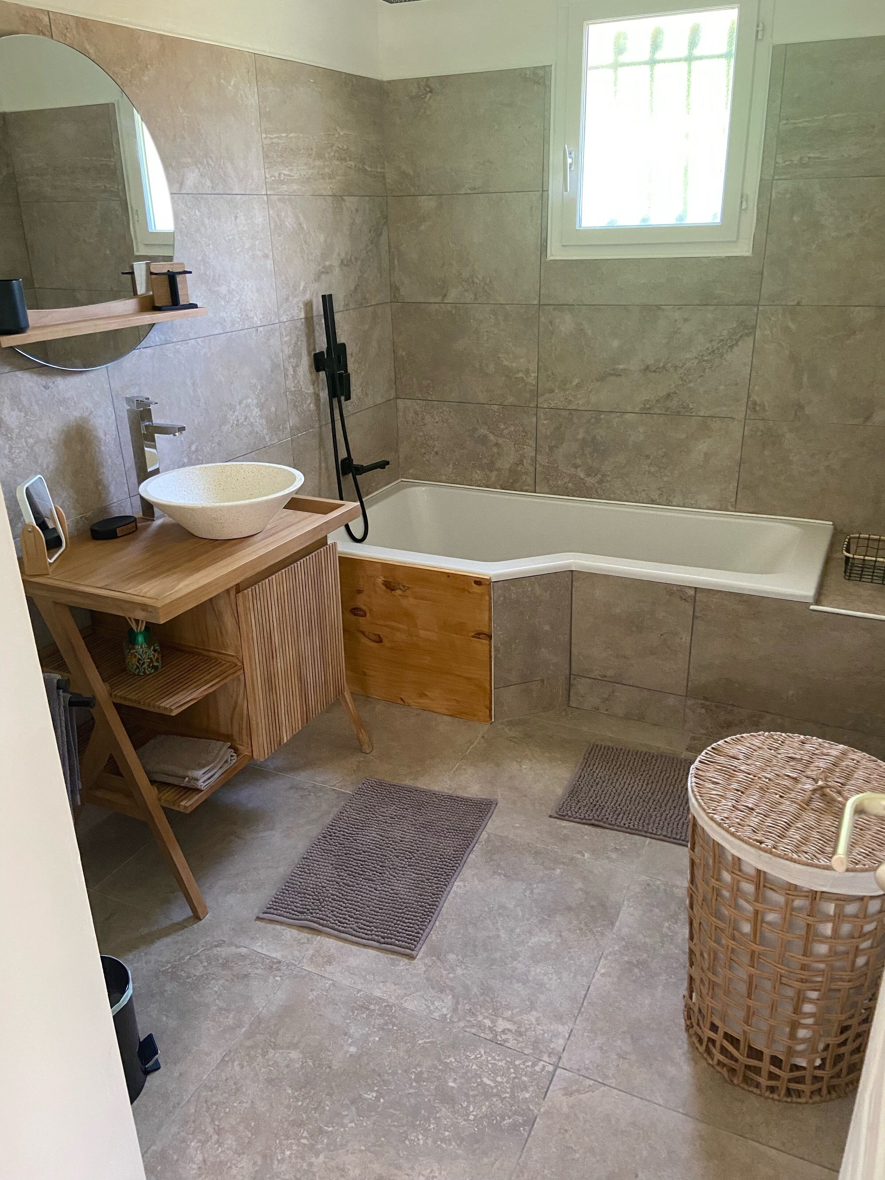 A modern bathroom with a freestanding bathtub, a large mirror, and a wooden vanity.