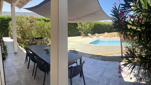 Un patio cubierto con piscina, mobiliario exterior y zona de barbacoa.