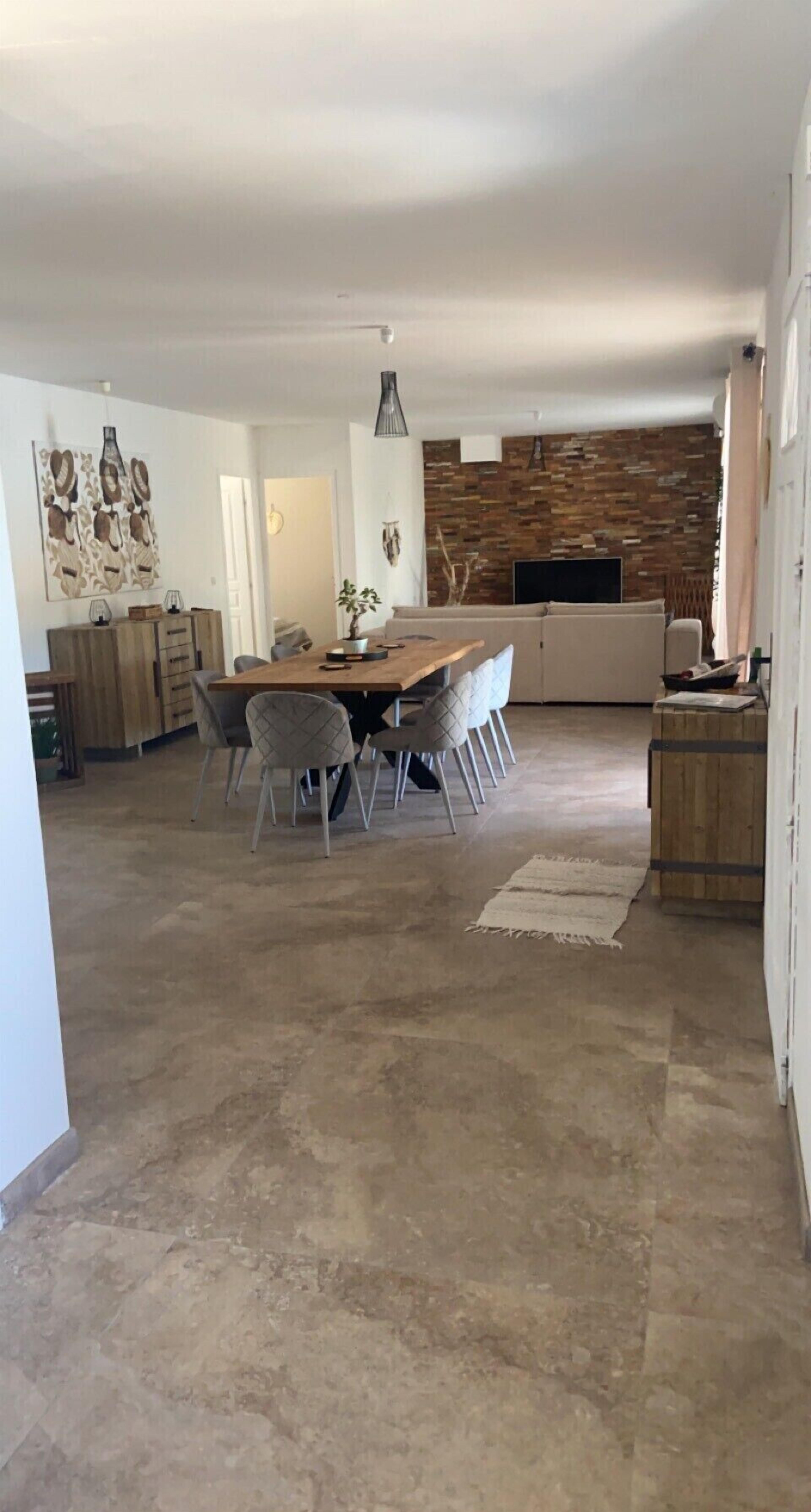 Een ruime woonkamer met een eettafel, stoelen, een bank en een televisie.