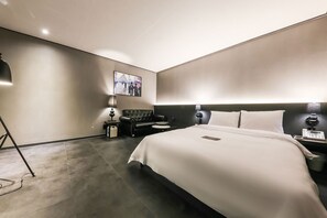 A modern hotel room with a large bed, a black leather sofa, a small round table, and a wall-mounted picture. - Hotel N7 Daejeon Bus Terminal (Daejeon)