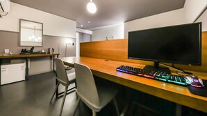A modern office space with a wooden desk, a computer monitor, a keyboard, and a mouse. There is a chair, a small kitchenette area, and a mirror on the wall. - Hotel N7 Daejeon Bus Terminal (Daejeon)