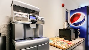A coffee machine with a digital display and buttons, a pizza box with various toppings, and a Pepsi logo on the wall. - Hotel N7 Daejeon Bus Terminal (Daejeon)