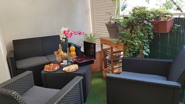 A patio area with wicker furniture, a table with food and drinks, and a potted plant.