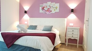 A bedroom with a bed, pillows, a bedside table, and wall-mounted lights.