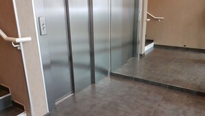 A modern elevator with a metallic finish, a handrail, and a control panel.