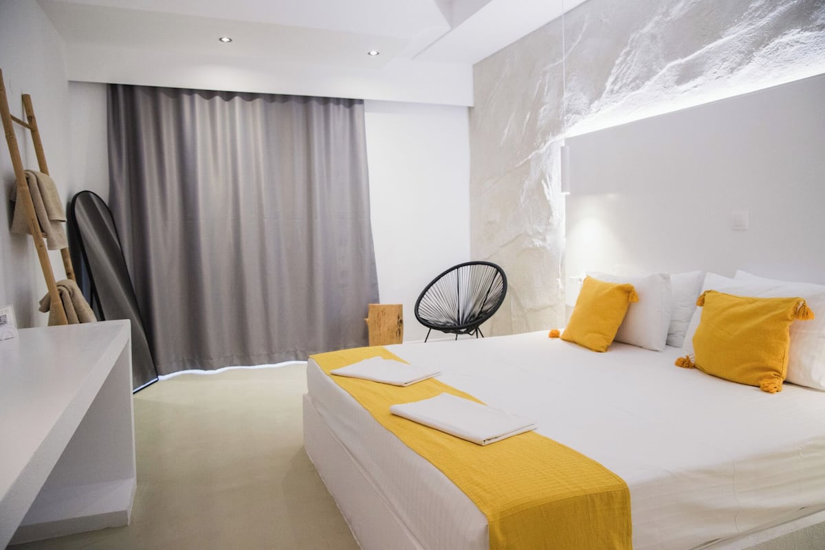 A modern hotel room with a large bed, a desk, and a chair.