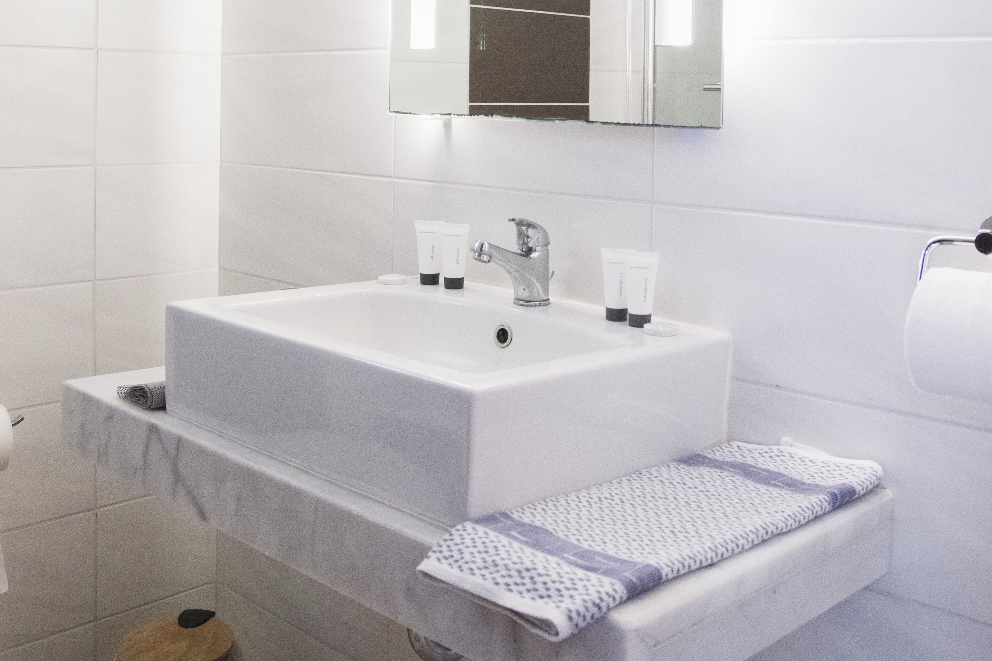 A bathroom with a white sink, a mirror above it, and a towel rack with a towel.