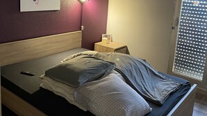 Un lit avec une tête de lit en bois, une table de chevet avec une lampe et un tableau accroché au mur.