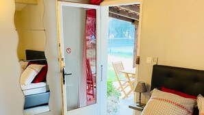 Une chambre à coucher comprenant un lit, une table de chevet, une lampe et une porte donnant sur un espace extérieur.