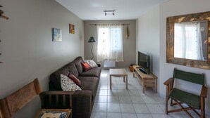 A living room with a sofa, a coffee table, a TV, and a chair. - Charming 3-Bedroom House Near Beach with Garden and Terrace (Les Sables-d'Olonne)