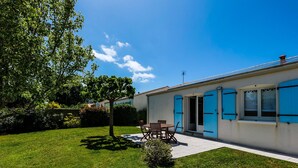 A house with a patio, a dining table, and blue shutters. - Charming 3-Bedroom House Near Beach with Garden and Terrace (Les Sables-d'Olonne)