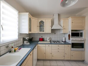 A kitchen with beige cabinets, a gas stove, a microwave, and a sink.