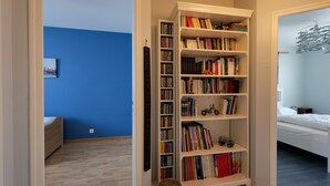 A room with a large bookshelf filled with books and toys, a bed, and a blue wall. - Charming 3-Bedroom House Near Beach with Garden and Terrace (Les Sables-d'Olonne)