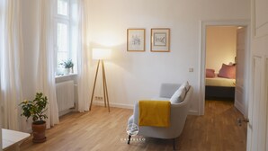 A modern living room with a grey sofa, a yellow throw, a floor lamp, and two framed pictures on the wall.