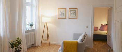A modern living room with a grey sofa, a yellow throw, a floor lamp, and two framed pictures on the wall.