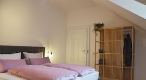 Un dormitorio con cama, armario y una planta colgante.
