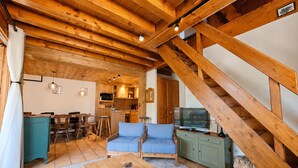 Um interior em madeira com área de refeições, cozinha e espaço para sentar.
