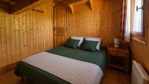 Um quarto com painéis de madeira, uma cama, uma mesa de cabeceira e uma janela com cortinas.