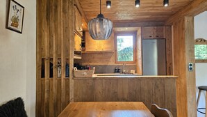 Interior em madeira com ilha de cozinha, iluminação pendente e uma janela.