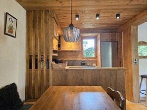 Un interno in legno con un'isola nella cucina, illuminazione a sospensione e una finestra.