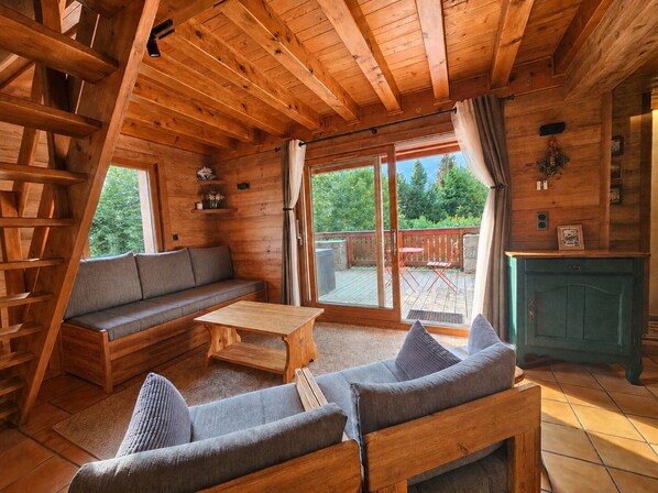 A wooden interior with a sofa, a table, and a fireplace.