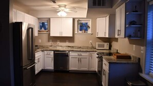 Una cocina con gabinetes blancos, un refrigerador de acero inoxidable, un microondas y un lavavajillas.