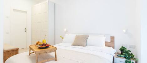 Un dormitorio con cama, mesita de noche y un velador con una planta.