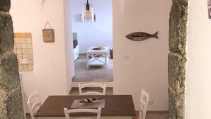 Uma área de refeições com mesa e cadeiras, um lustre e uma decoração de peixe na parede.