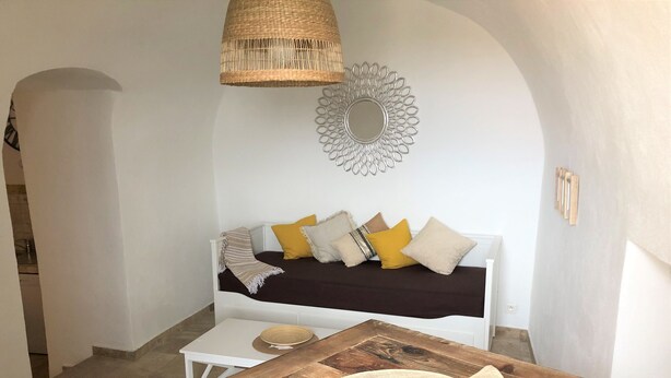 Um quarto aconchegante com um sofá branco, uma mesa de madeira e um lustre.