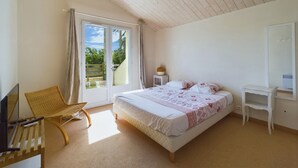 Ein Schlafzimmer mit einem Bett, einem Sessel, einem Fernseher und einem Schreibtisch.