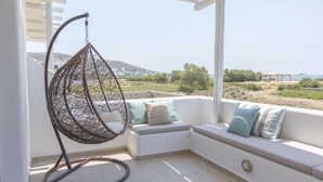 A balcony with a hanging chair, cushioned seating, and a view of the landscape. - Villa Lantana - Salinus Naxian Villas (Naxos)