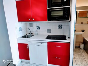 A compact kitchen with red cabinets, a Bosch dishwasher, a microwave, and a sink.