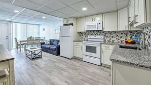 Una cocina moderna con armarios blancos, microondas, horno y encimera de granito.